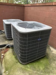 Two air conditioners are sitting outside in a room.