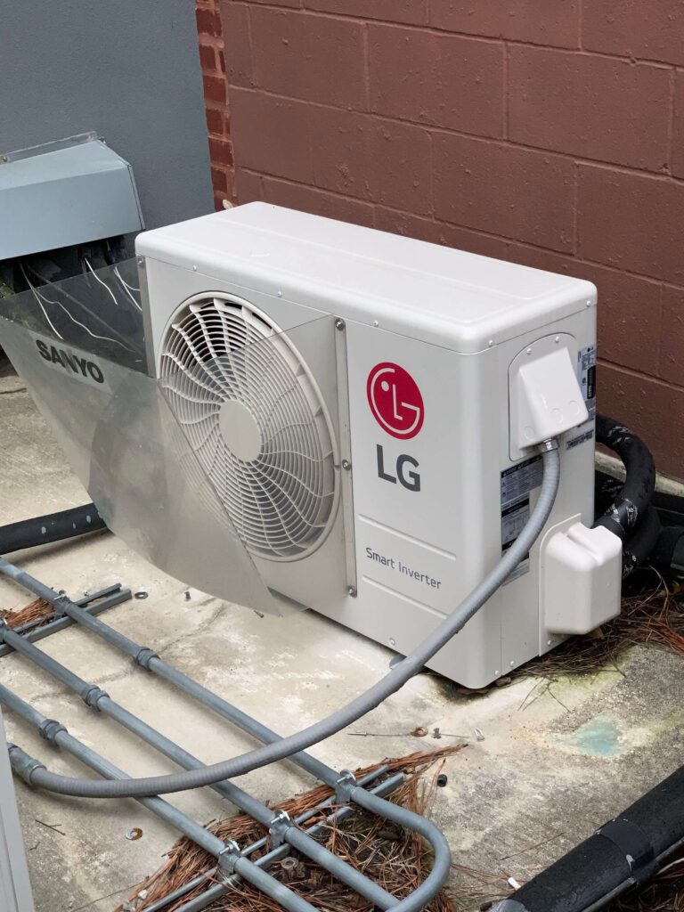 A white air conditioner sitting on top of the ground.