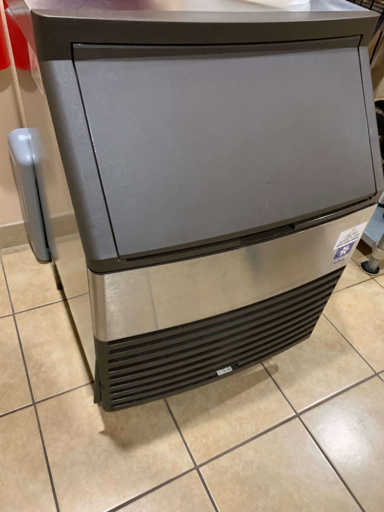 A large ice machine sitting on top of a tiled floor.