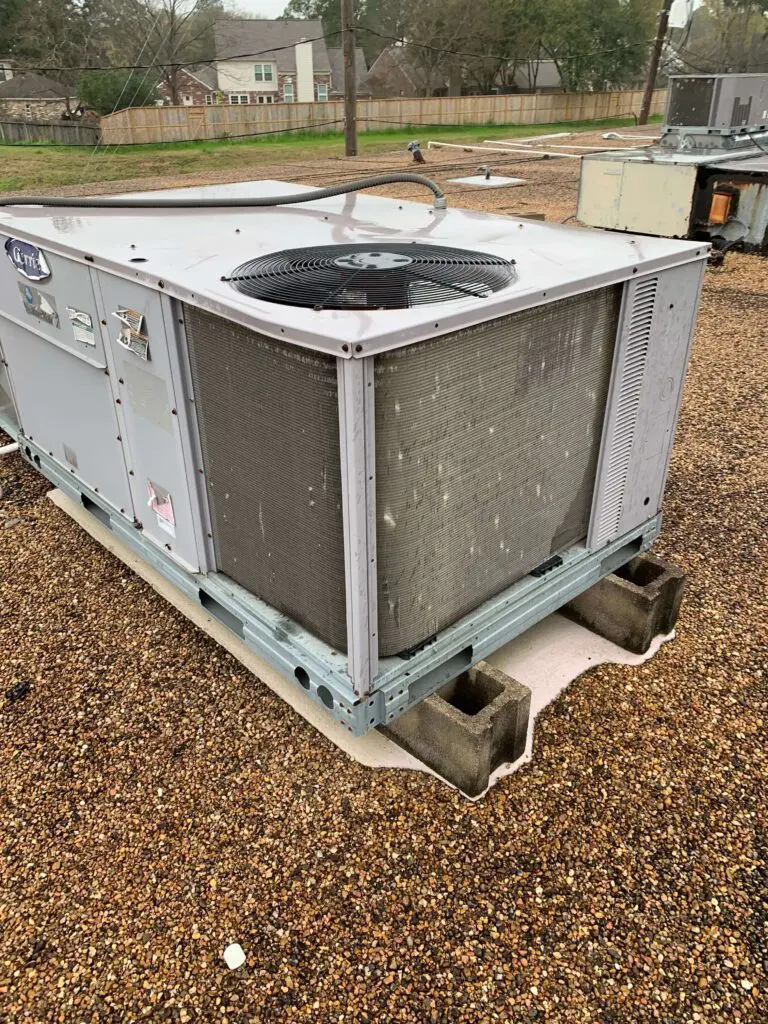A large air conditioner sitting on top of a gravel ground.